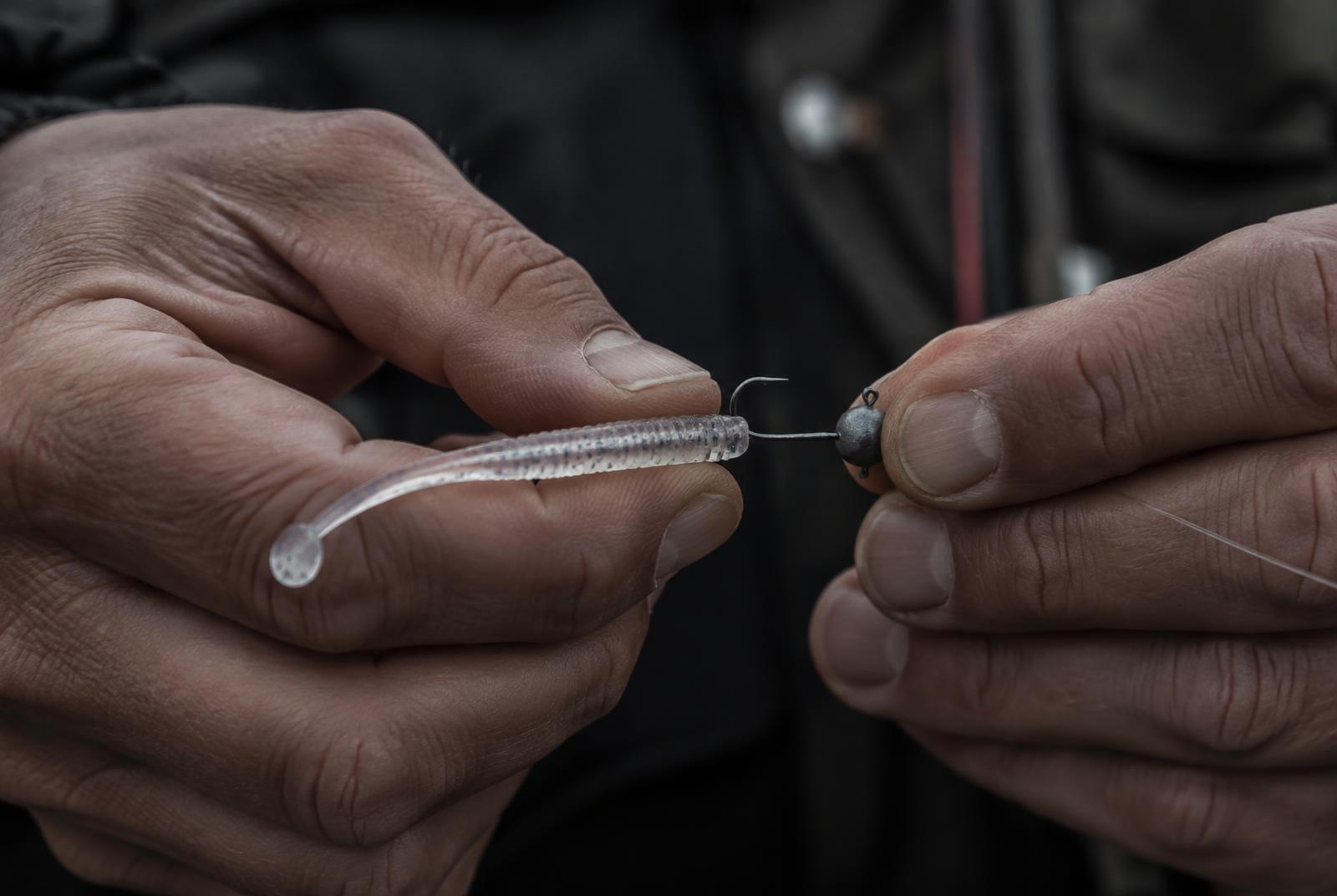 Mains montant un petit leurre souple sur une tête plombée